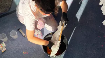 Frau färbt Stoff im Eimer auf Boden.