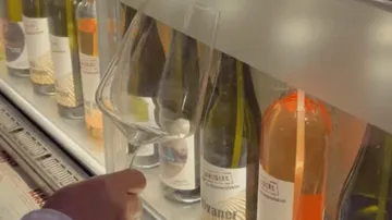Hand hält Glas am Weinspender.