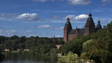 Castle beside river surrounded by trees.