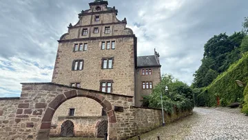 Historisches Steingebäude mit Torbogen, bewölkter Himmel.
