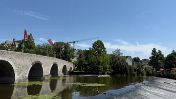 Stone bridge arches over calm river.