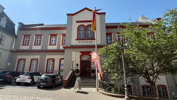 Rathaus mit Fahnen und geparkten Autos.