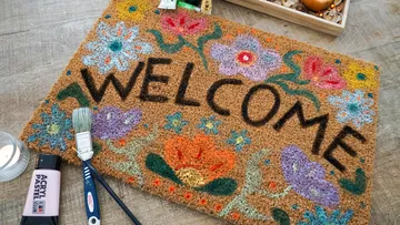 Colorful welcome mat with flowers and art supplies.