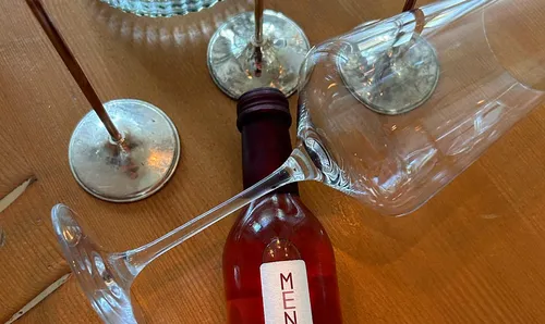 Wine bottle under tilted wine glasses.