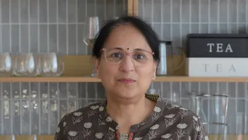 Person standing in front of kitchen shelves.