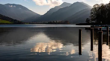 Berge spiegeln sich in ruhigem See bei Sonnenuntergang.