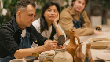People discussing pottery techniques at a table.