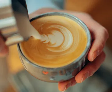 Tasse Kaffee mit kunstvollem Milchschaum-Muster.