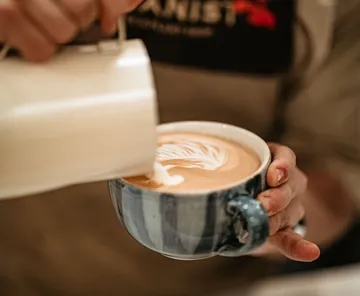 Barista gießt Latte Art in Tasse.
