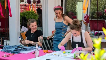 Three women crafting outdoors, smiling.