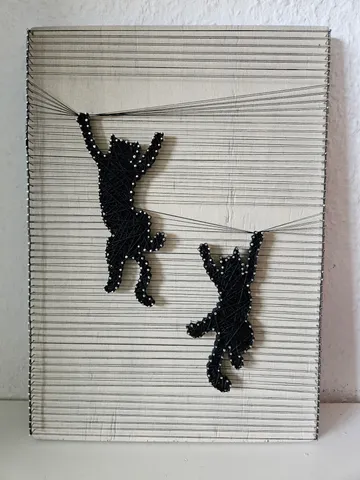 String art cats hanging on wires.