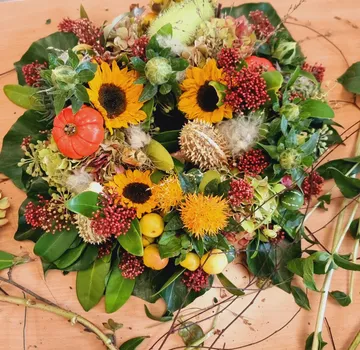 Blumenkranz mit Sonnenblumen auf Tisch.
