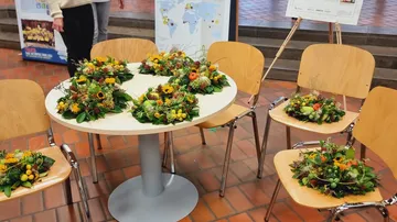 Table with floral arrangements, surrounded by chairs.