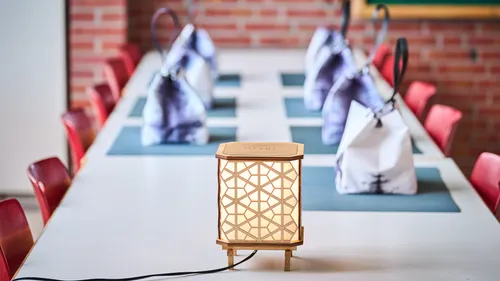Holzlampe auf Esstisch mit Taschen.