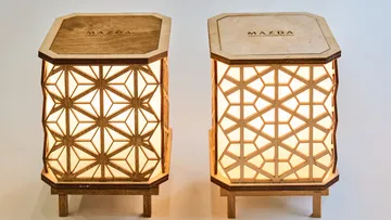 Zwei Holzlampen mit geometrischen Mustern leuchten.