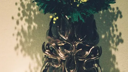 Decorative vase holds vibrant green and yellow flowers.