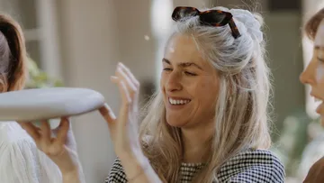Woman holding ceramic plate, smiling outdoors.