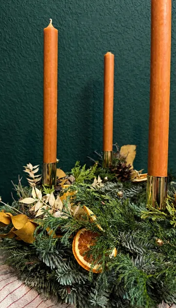 Orange candles in a decorative wreath setting.