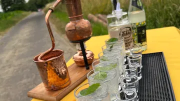 Copper still with glasses outdoors.