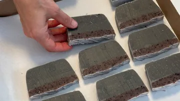 Hand arranging homemade grey soap bars.