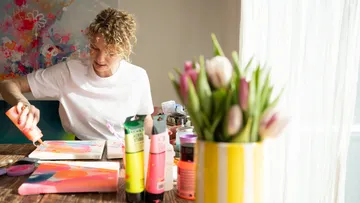 Person painting at table with tulips.
