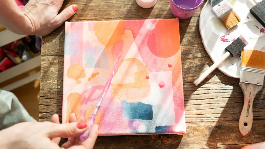 Person painting colorful abstract canvas indoors.