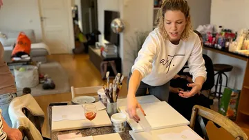 Frau ordnet Gegenstände auf Tisch im Raum.