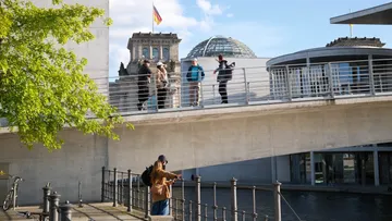 People walking on bridge near German Parliament.
