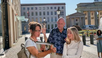 Touristen mit Reiseführer am Brandenburger Tor.