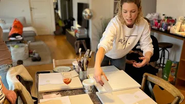 Frau bereitet Kunstmaterial am Werkstatttisch vor.