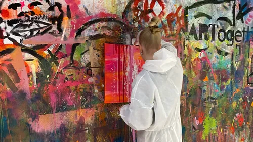 Person painting on colorful graffiti wall.