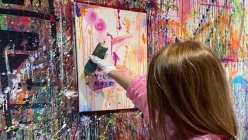Person painting colorful canvas in studio.