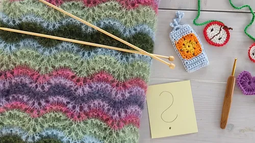 Knitted scarf with crochet items on wooden table.