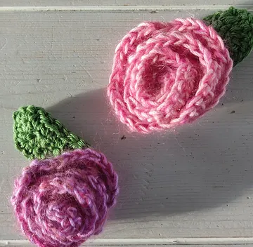 Two crocheted flowers on a wooden surface.