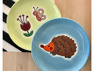 Bunte Teller mit Zeichnungen von Blumen, Schmetterlingen und Igel.
