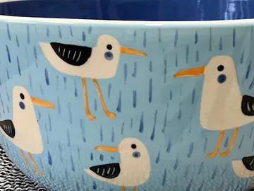 Colourfully painted bowl with birds on a blue background.