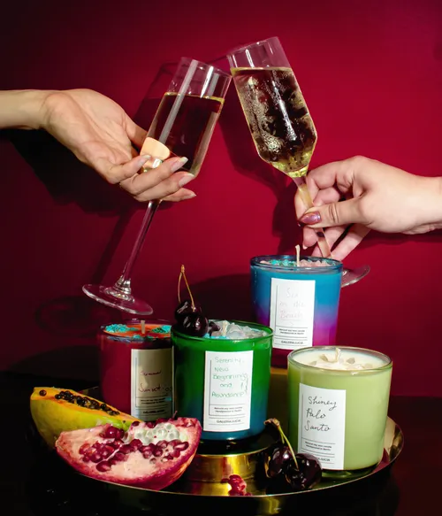 Two glasses clinking above colorful candles.