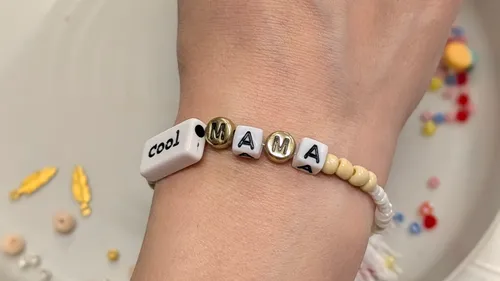 Hand trägt ein buntes Perlenarmband.