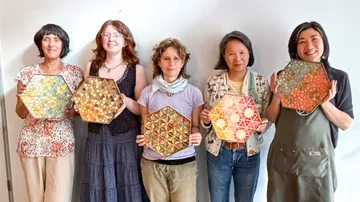 Fünf Personen halten bunte sechseckige Mosaikkunst.