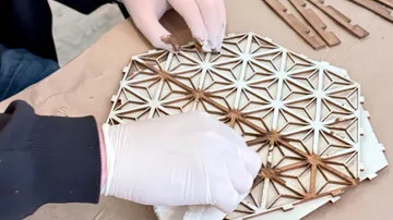 Hände montieren geometrisches Holzmuster.