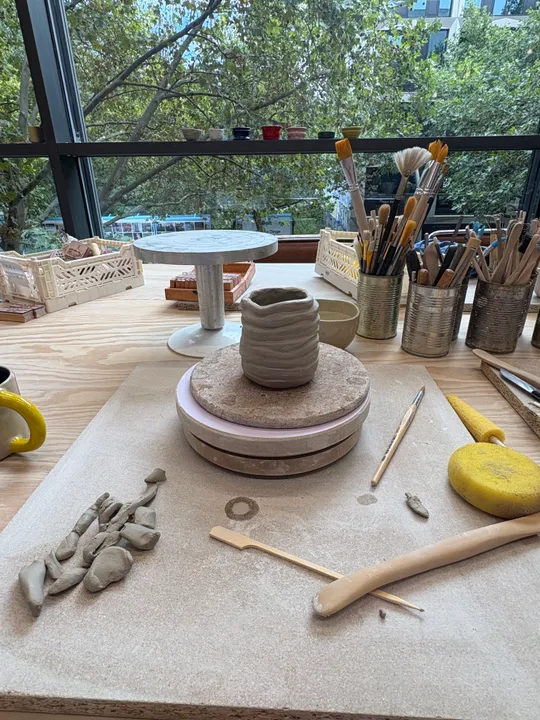 Pottery wheel on table beside art tools.