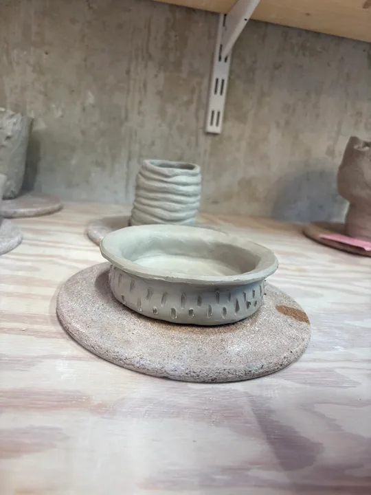 Clay pottery drying on wooden table.