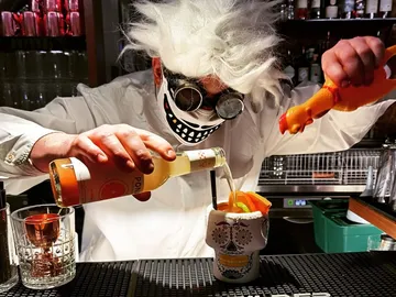 Bartender mit verrückter Frisur mixt Cocktails in einer Bar.