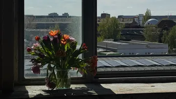 Blumenstrauß auf Fensterbank mit Stadtlandschaft.