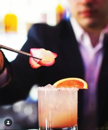 Bartender garnishes cocktail with flower petal