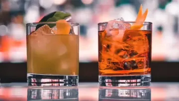 Two cocktails on bar counter, blurred background.