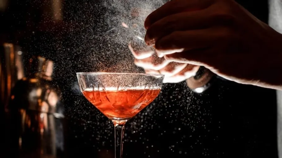 Glass being garnished with citrus zest.