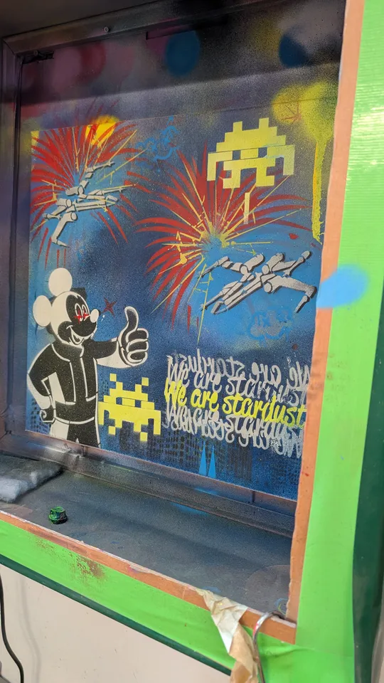 Graffiti einer Cartoonfigur mit Retro-Spielsymbolen.