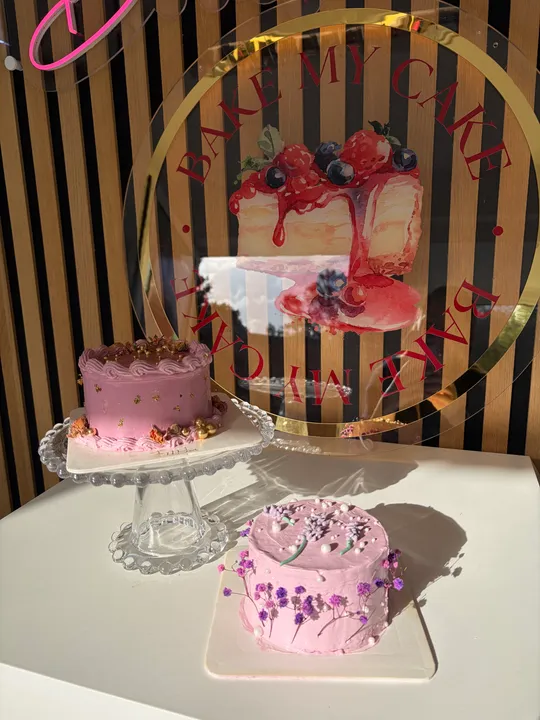 Zwei rosa Torten mit Blumendekor auf Tisch.