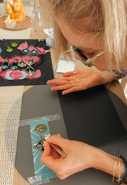 Person crafting jewelry on a table.